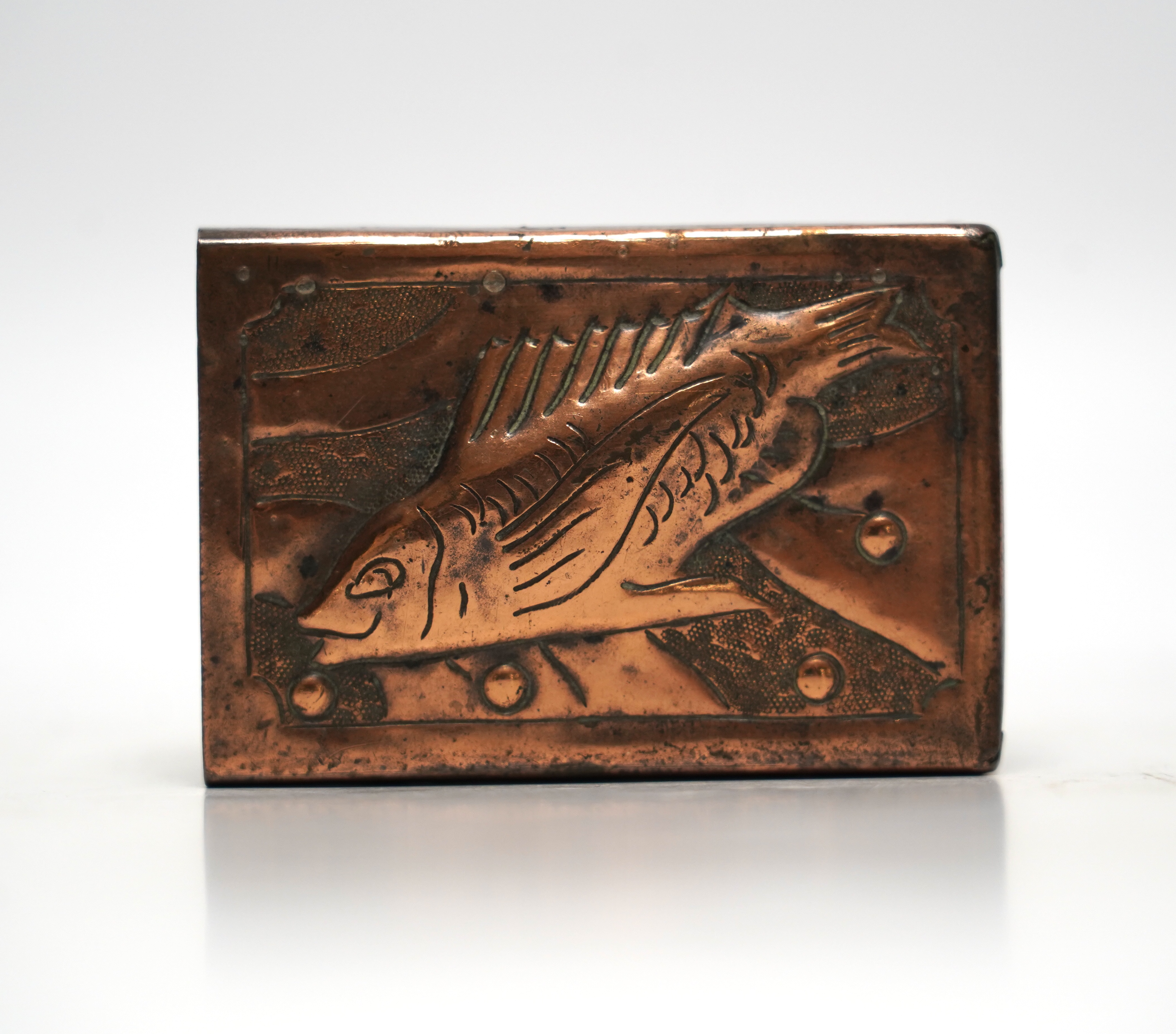 A Newlyn copper matchbox cover, decorated with a fish, 7.5cm wide